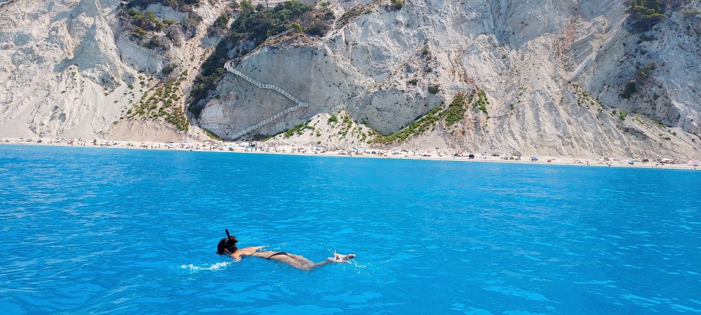 A beautiful young woman snorkeling in the crystal clear blue sea close to Egremni beach in Lefkada Greece during a private boat cruise